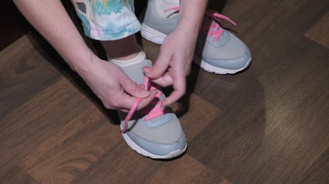 How to tie shoelaces with pink laces on gray sneakers indoors