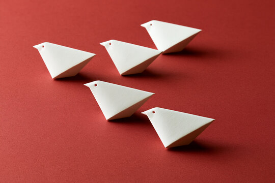 Five white paper bird ornaments arranged on red