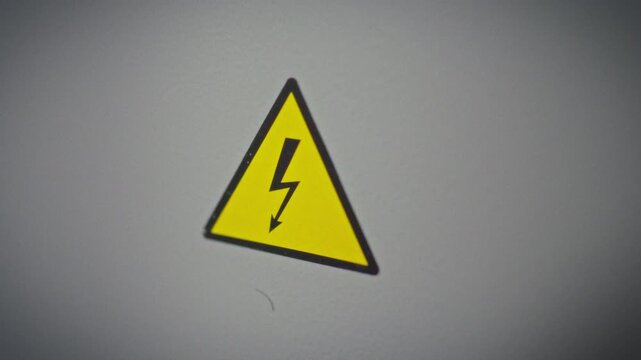 A close-up of an electrical hazard symbol mounted on an electrical panel cover. Concept of safety marking and high voltage warning in home electrical installations