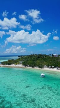 Aerial cloudscape over turquoise island, billowy white clouds above lush green shoreline, white sand beach and distant floating dome, expansive horizon and cinematic sky, Himmafushi island, Maldives