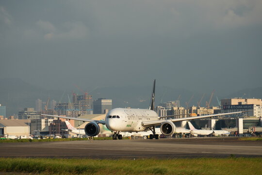 Passenger airplane taxiing on the runway with urban background.