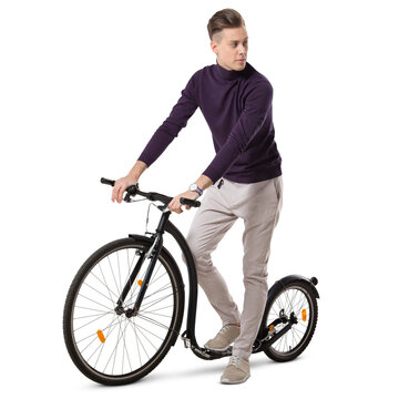 Young man riding a trendy big wheel scooter, isolated on white and transparent background.
