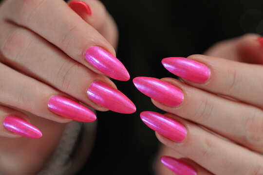 beautiful female hands with long nails and bright neon pink red nail polish