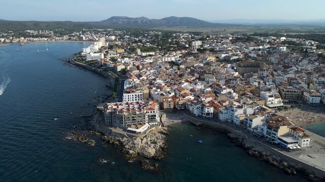 High wide aerial view of L'Escala coastal town with Platja de les Barques beach and La Punta headland. Panorama of Costa Brava, Girona, Catalonia, Spain