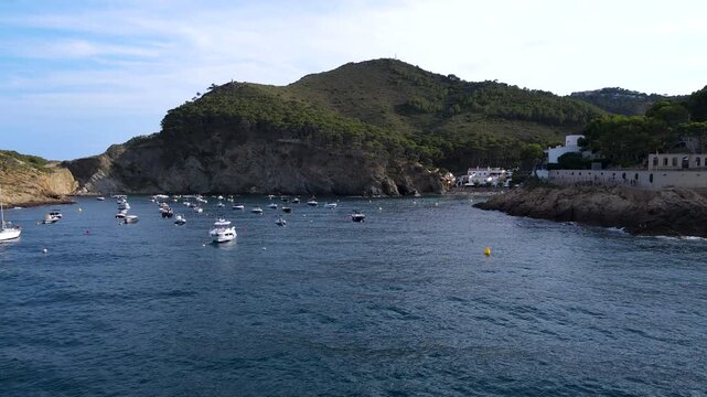Small boats anchored inside sheltered Cala d'Aiguafreda in Begur. Aerial footage of Costa Brava, Girona, Catalonia, Spanish coast