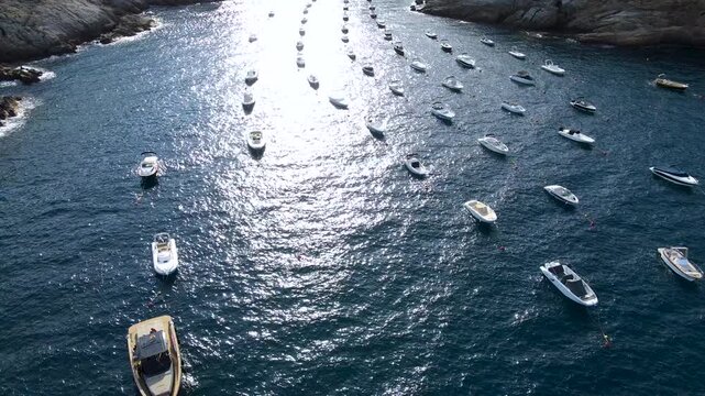 High angle view of small pleasure boats moored on sparkling Mediterranean water. Aerial footage of Cala d'Aiguafreda, Begur, Costa Brava, Girona, Catalonia, Spain