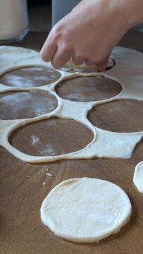 Woman hands making traditional pierogi dumplings at home kitchen table, rolling pin and raw dough preparing delicious homemade meal, authentic culinary workflow process for Polish cooking concept