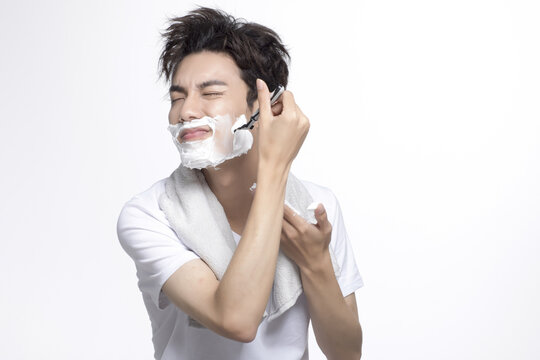 Young man shaving with foam in studio setting