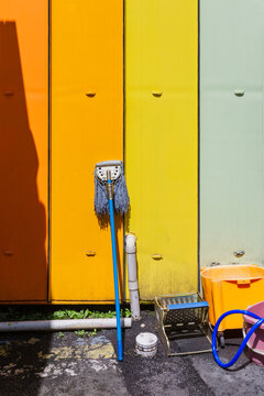 Cleaning Mop and Yellow Bucket in Front of Colorful Container Wall