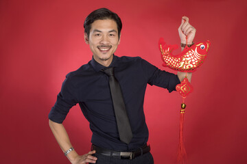 Happy Asian man holding a red and gold fish ornament for Chinese New Year © LaDieuNgoc