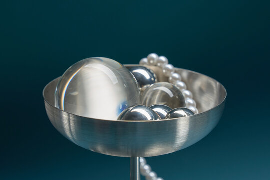 Pearls and silver spheres in metal bowl