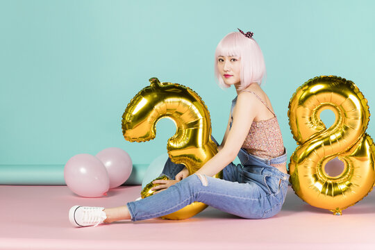 Stylish Woman Celebrating 28th Birthday with Golden Balloons