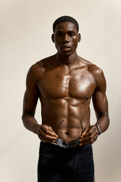 Model poses in a studio setting without a shirt and holding sung