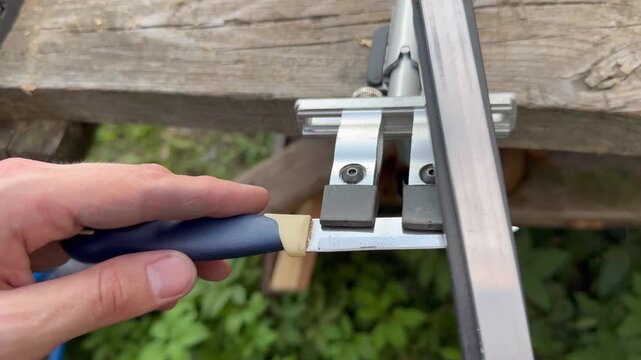 Manual knife sharpener tool system assembled on wooden table outdoors.