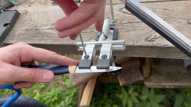 Close up of clamping kitchen knife blade into manual knife sharpener system.