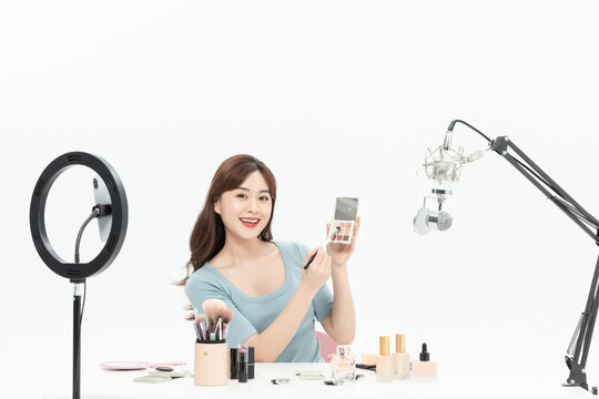 Beauty influencer hosting a live makeup stream with ring light and microphone