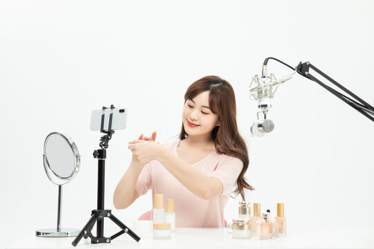 Young Asian Woman Livestreaming Skincare Routine with Smartphone and Microphone