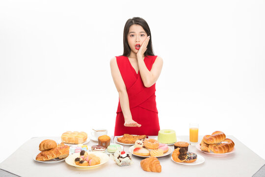 Shocked Woman Resisting Temptation of Sweets and Pastries at a Table