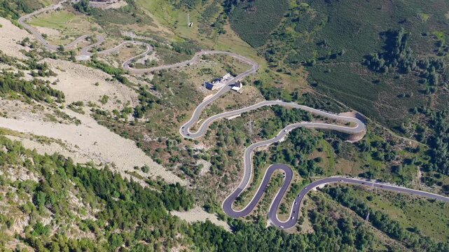 Aerial view of cars driving along winding S-curves on C-28 mountain road to Baqueira Beret during summer road trip, Spain