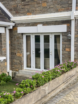white french doors on stone cottage exterior, glass panels in soft focus with copy space, residential architecture background concept