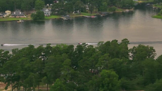 Jet skis racing on a lagoon in the afternoon, amidst trees and vacation homes..