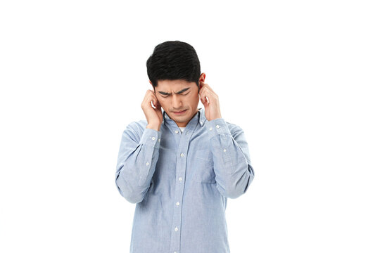 Young man covering his ears with hands, suffering from loud noise