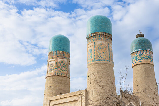 Chor Minor towers with turquoise domes in Bukhara, Uzbekistan, viewed against a bright sky. Historic Islamic architecture ideal for travel guides and cultural publications.