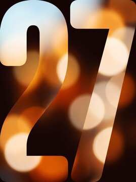 Oversized golden amber bokeh New Year number 27 cropped by frame edges with glowing light orbs