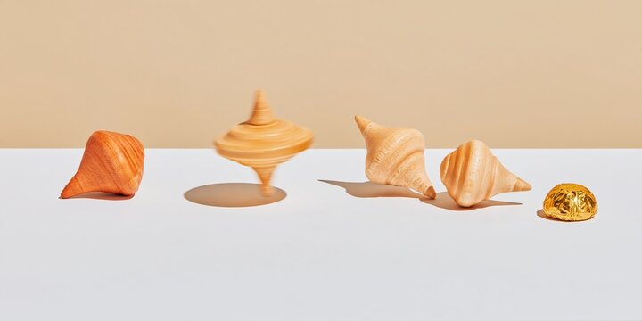 Wooden dreidel sequence showing four stages of a spin on a smooth white surface with a gold chocolate coin for holiday explainers