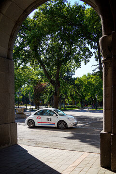 Vertical shot of a white Volkswagen New Beetle styled as Herbie the Love Bug with number 53 racing livery, driving framed by large stone archway of City Hall, Subotica, Serbia, Jul 4, 2026