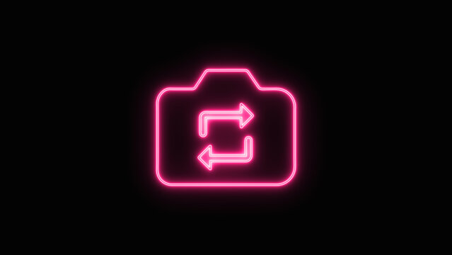 Glowing colorful neon icon of a digital photography camera with rotation arrows symbolizing the switch camera or selfie mode function isolated on black background