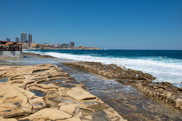 Rock cut traditional Roman baths along the Sliema coastline with sea waves in Malta © Aleksandar