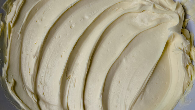 Swirled buttercream frosting background with textured ridge patterns close up macro