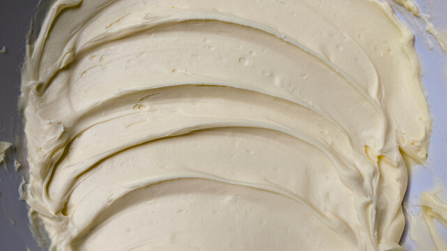 Whipped buttercream frosting textured background with swirled ridge patterns close up
