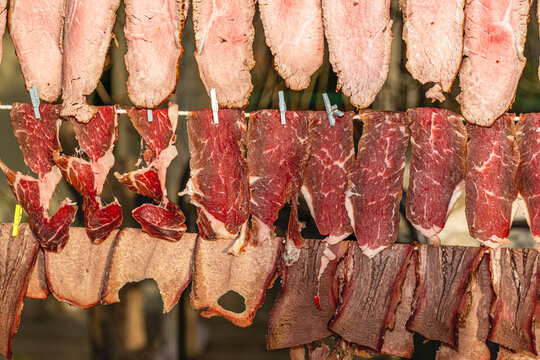 Variety of traditional smoked meats and artisanal sausages displayed on a market food stand counter.
