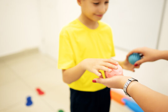 School age child participates in a sensory motor exercise with a therapist using textured therapy balls, developing hand coordination, motor planning and sensory processing skills.