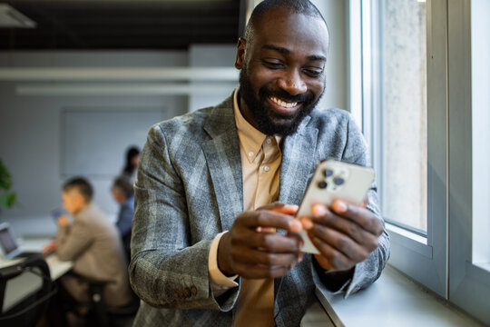 Smiling professional using smartphone by office window