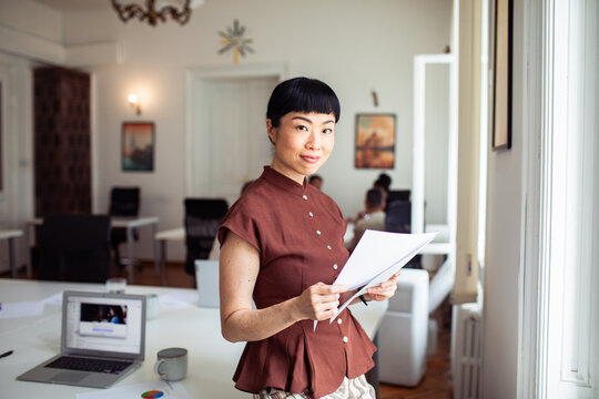 Confident businesswoman reviewing documents in bright office