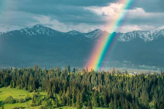 Majestic panoramic view of the Tatra Mountains landscape featuring snow-capped peaks, colorful forests, and picturesque valleys under a dramatic sky. Beautiful scenic nature and wilderness background