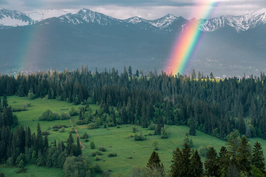 Majestic panoramic view of the Tatra Mountains landscape featuring snow-capped peaks, colorful forests, and picturesque valleys under a dramatic sky. Beautiful scenic nature and wilderness background