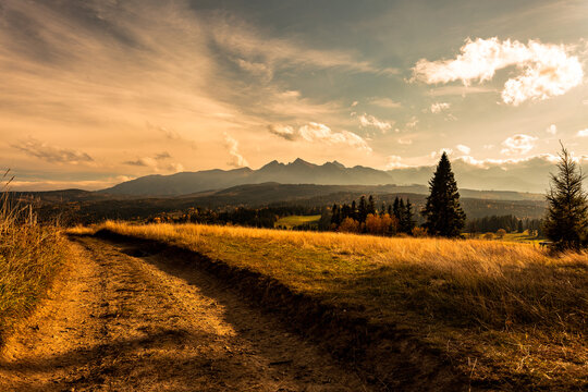 Majestic panoramic view of the Tatra Mountains landscape featuring snow-capped peaks, colorful forests, and picturesque valleys under a dramatic sky. Beautiful scenic nature and wilderness background