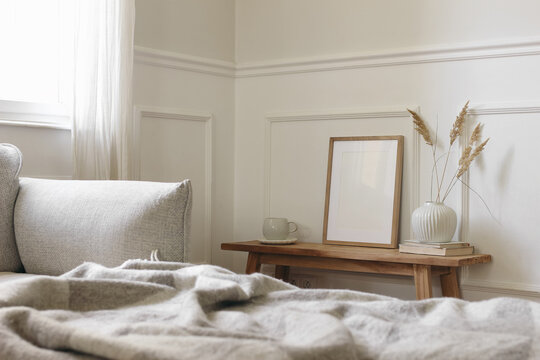 Cozy Scandinavian Style Bedroom Living Room Interior. Soft Beige Bedding, Wooden Bench. Blank Picture Frame Poster Mockup. Ceramic Vase with Dried Grasses. Natural Decor, Neutral Home Design, daylight