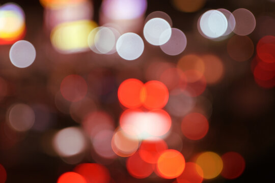 Abstract out-of-focus city night lights creating vibrant colorful bokeh orbs in shades of red, white, yellow, and orange, perfect as a decorative background.