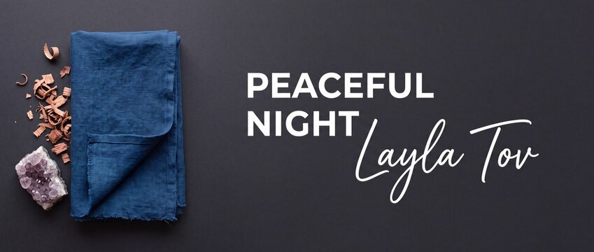 Peaceful night Layla Tov background featuring folded blue linen cloth, natural amethyst crystal, and aromatic wood shavings on dark flat lay surface for Jewish relaxation, spa concept, and banner.