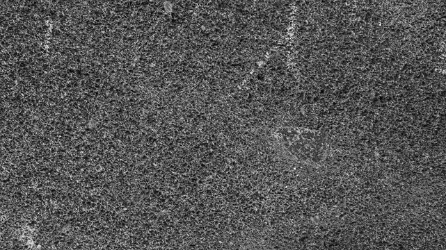 Close-up of a dark gray rough surface with dense granular details, irregular particles, and a naturally uneven pattern.