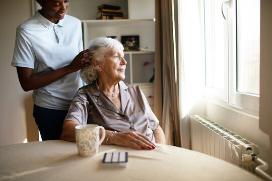 Caregiver fixing senior woman?s hair at home