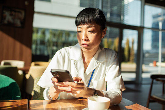 Healthcare worker checking smartphone during coffee break in cafe