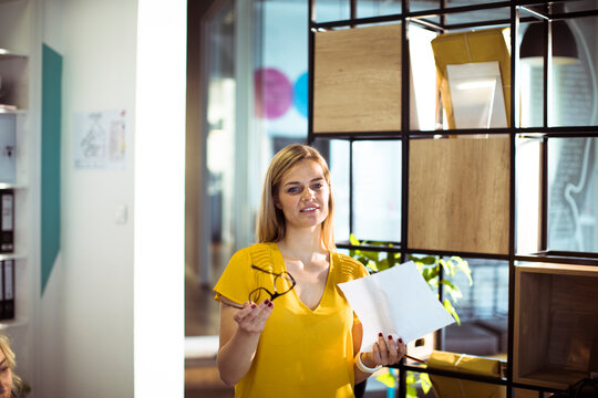 Woman presenting with paper and glasses in modern office