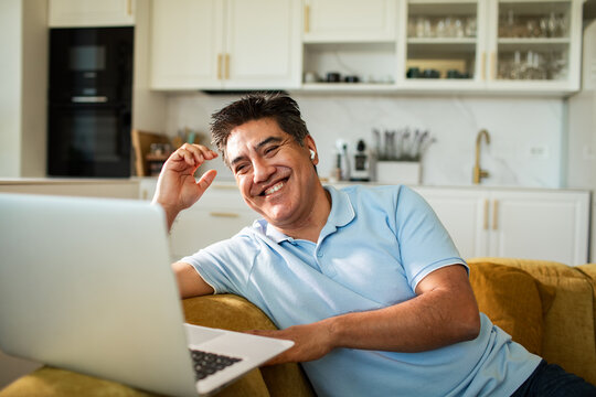 Smiling man video chatting on laptop at home