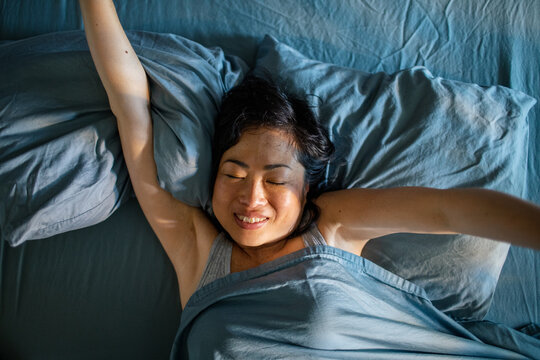 Smiling woman stretching in bed in the morning